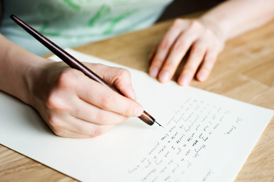 Una persona escribiendo en un folio usando una pluma estilográfica.
