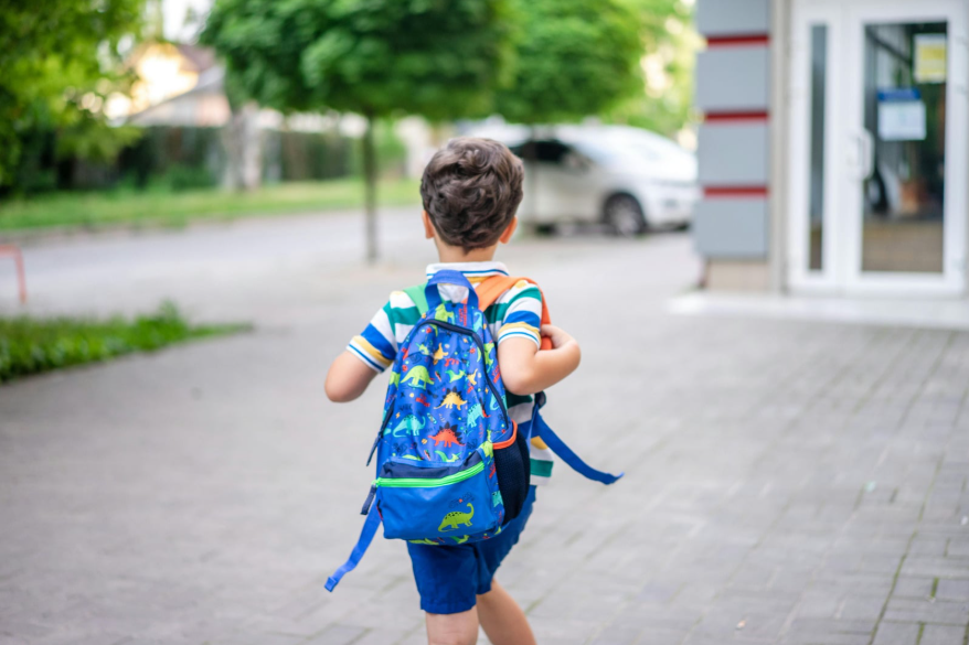 Un niño con una mochila a cuestas corriendo.